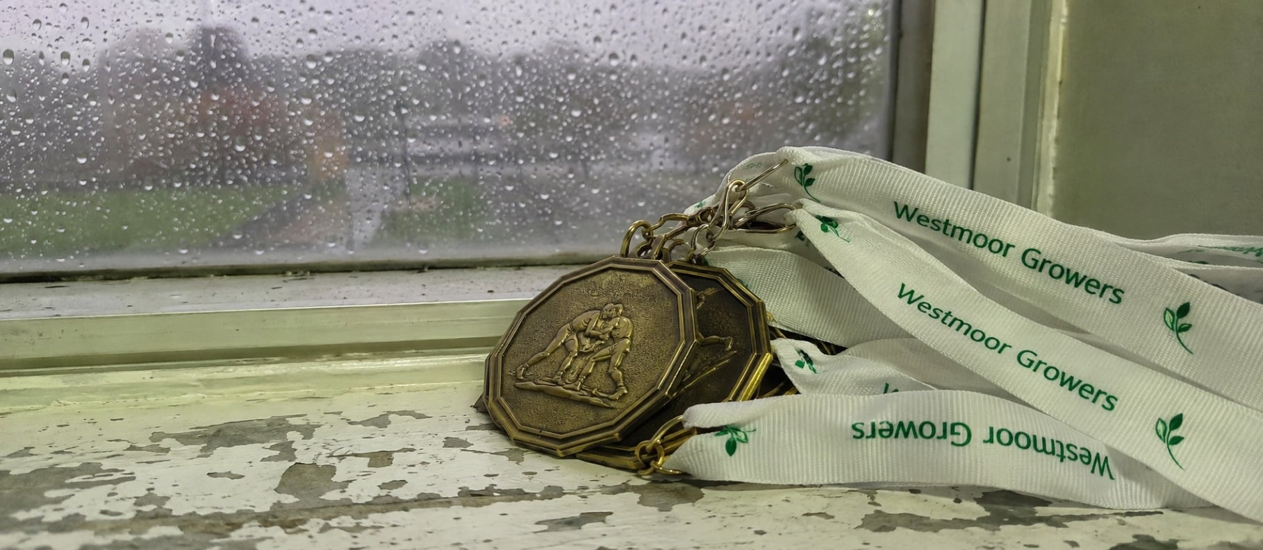 Custom wrestling medals with printed ribbons laid out on a gym bench